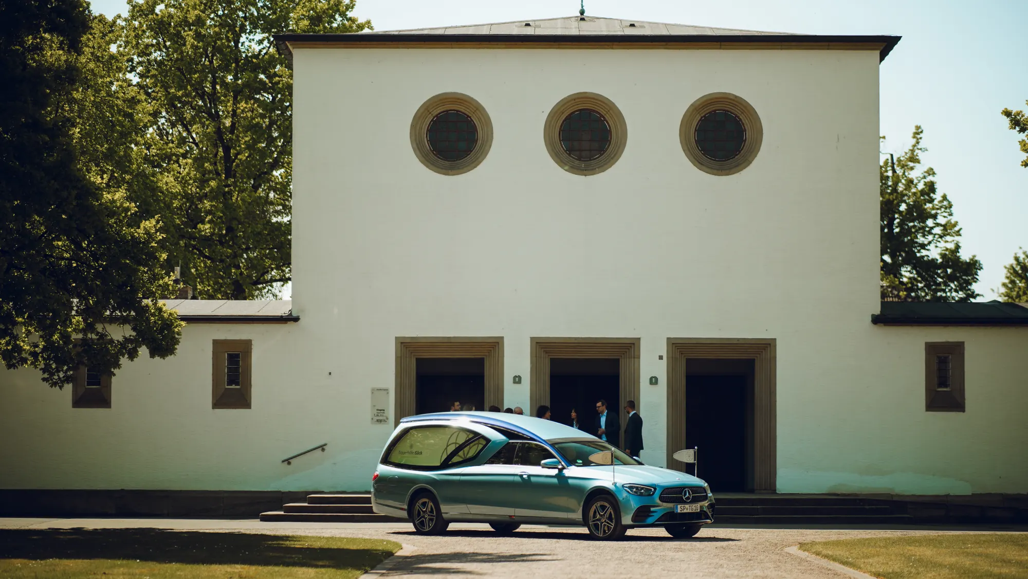 Trauerhalle auf dem Friedhof mit dem Bestattungswagen der Trauerhilfe Göck davor